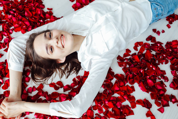 beautiful woman lies among the red petals of rose flowers - Foto, Imagen