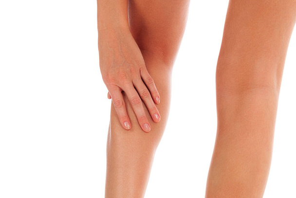 Woman touches her painful shin, isolated on white background - Photo, Image