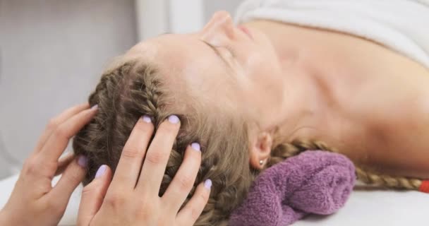 Mulher jovem recebendo massagem na cabeça relaxante no centro de spa. massagista fazendo massagem na cabeça no centro de bem-estar.  - Filmagem, Vídeo