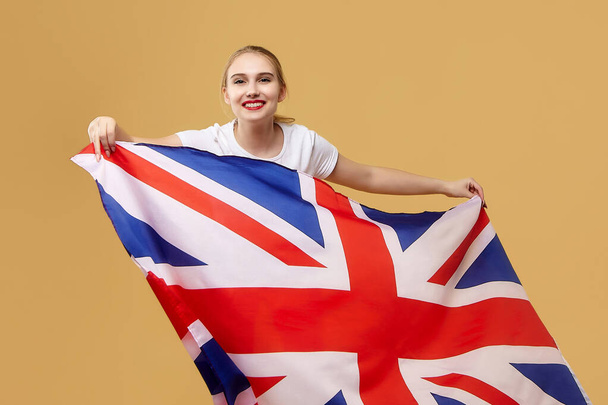 attractive blonde poses with a British flag. photo shoot in the studio on a yellow background. - Foto, afbeelding