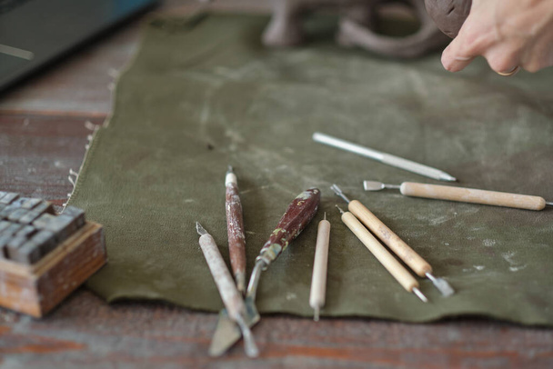 глина и инструменты лежат на столе перед ноутбуком. Керамика онлайн обучение концепции. видео-уроки для хобби. Керамические инструменты - Фото, изображение