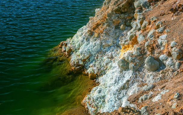 Mining tailings and toxic waste at a shore of an abandoned open pit copper mine. Crystals of iron sulfate and contaminated water close up - Photo, Image