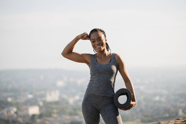 Smiling african woman showing her biceps outdoors - Φωτογραφία, εικόνα