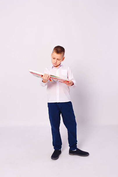 ten-year-old boy in school uniform with books in his hands stands in full height on a white background - Fotografie, Obrázek