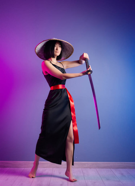 esbelta mujer asiática un sombrero asiático con una katana en la mano imagen de un samurai - Foto, Imagen