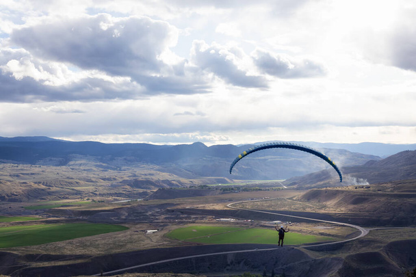 Adventurous Man Flying on a Paraglider around the mountains. - Fotó, kép
