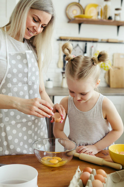 Sevimli küçük kız, annenin mutfakta kurabiye pişirmesine yardım ediyor. Mutlu bir aile. Tonlama. - Fotoğraf, Görsel