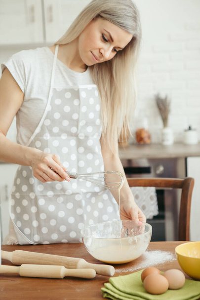 Young beautiful woman kneads dough for baking cookies in the kitchen. Toning. - Foto, afbeelding