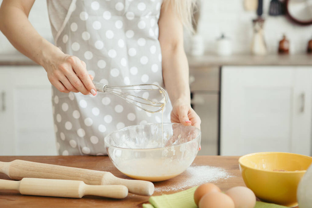 Young beautiful woman kneads dough for baking cookies in the kitchen. Toning. - Foto, Bild