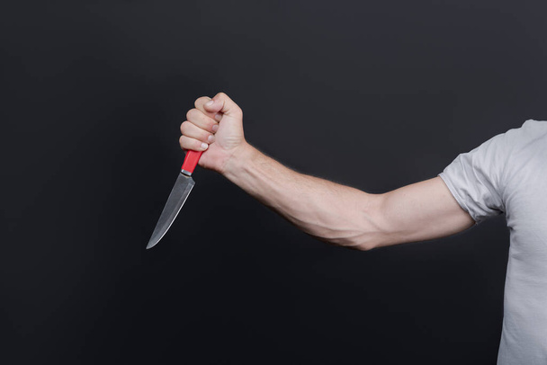 Close up of man holding a Metal knife in the hand. The criminal with a knife weapon threatens to kill. With space for an inscription. Murderer, killer is attacking with knife. Domestic violence - Photo, Image