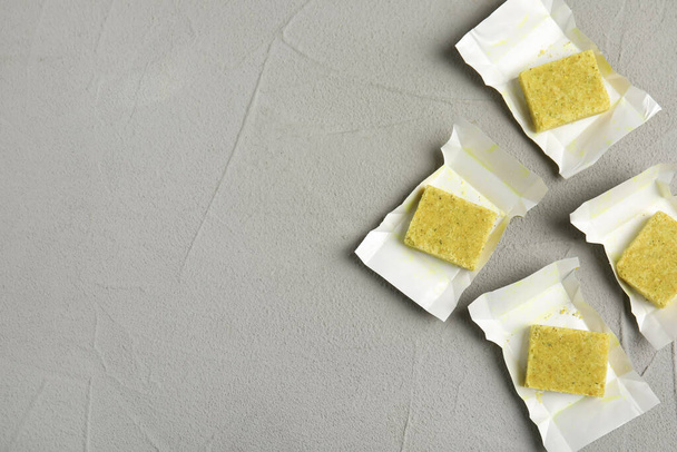 Bouillon cubes with wraps on light grey table, flat lay. Space for text - 写真・画像