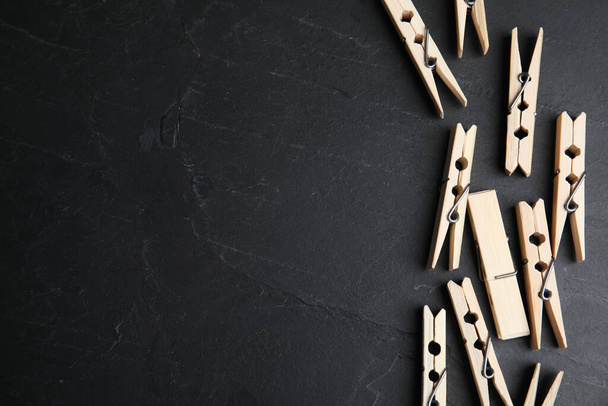 Wooden clothespins on black slate table, flat lay. Space for text - Fotoğraf, Görsel