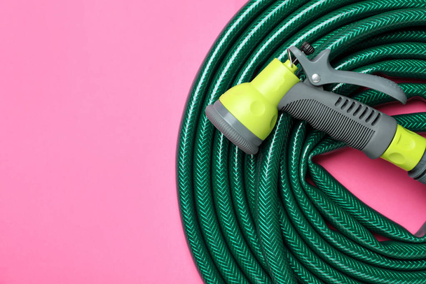 Watering hose with sprinkler on pink background, top view. Space for text - Zdjęcie, obraz