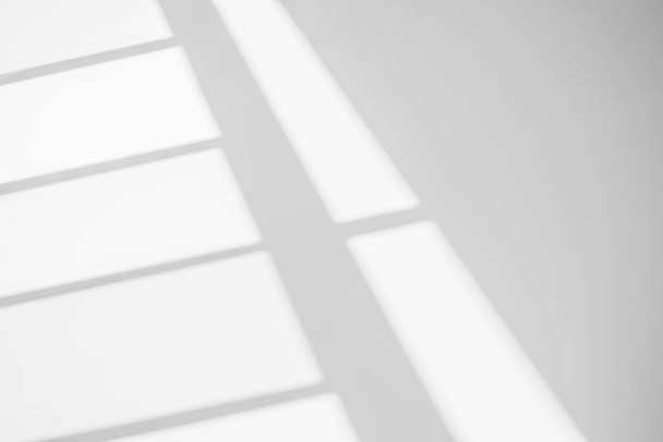 Sombra de la ventana fondo borroso abstracto con reflejo de luz y sombra gris de la ventana en la pared blanca, gris oscuro y sol efecto geométrico diagonal superposición para el telón de fondo y maqueta desig - Foto, Imagen