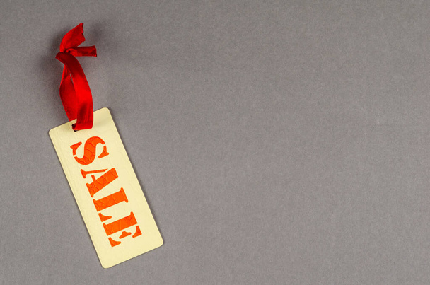 Rectangular sale tag on gray background. Paper tag with red ribbon. Concept for sales promotion. Sale. Copy space. - Φωτογραφία, εικόνα