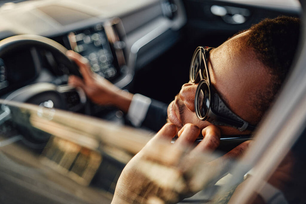 Black business man talking on his phone inside of car - Foto, Bild