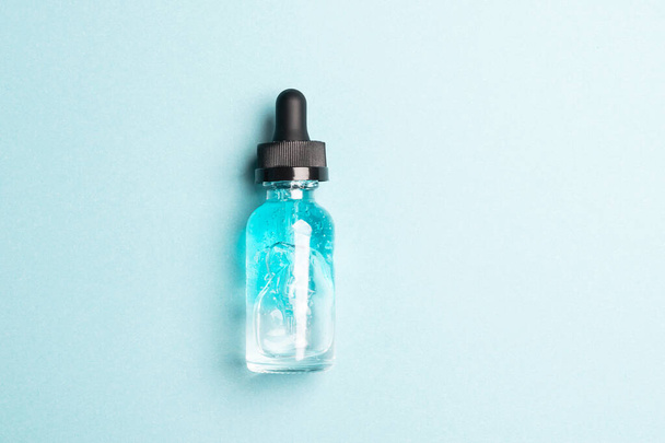 Lubrificante de soro de gel líquido cosmético em frasco de vidro transparente com pipeta conta-gotas sobre fundo azul - Foto, Imagem