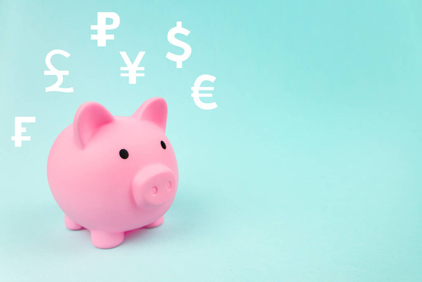 Economia financeira e bancária. Banco piggy rosa com moedas mundiais do holograma digital no fundo azul. Conceito de câmbio global - Foto, Imagem