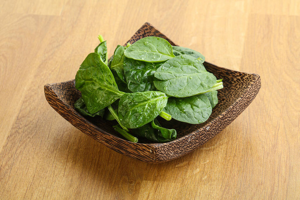 Verse groene spinazie bladeren in de kom over houten ondergrond - Foto, afbeelding