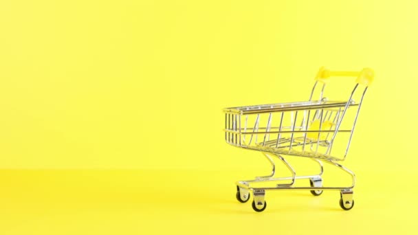 Leere Einkaufswagen auf gelbem Hintergrund, Nahaufnahme. Black Friday Shopping und Discount-Konzept - Filmmaterial, Video