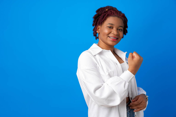 African American woman feeling strong, showing fist against blue background - Fotó, kép