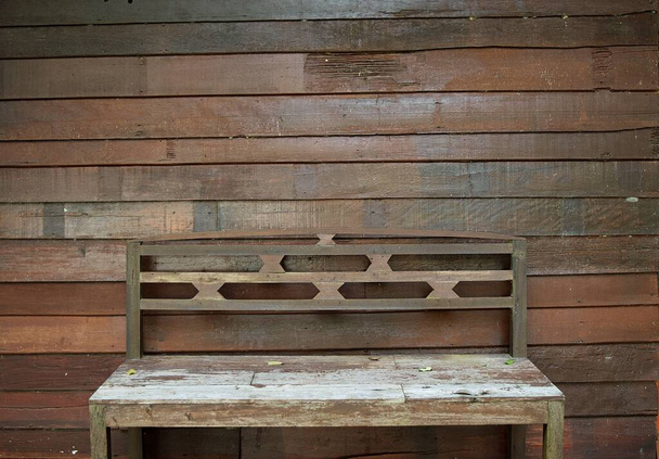 Винтажная деревянная скамейка с коричневыми досками стены в качестве фона, текстура для добавления текста или графического дизайна   - Фото, изображение