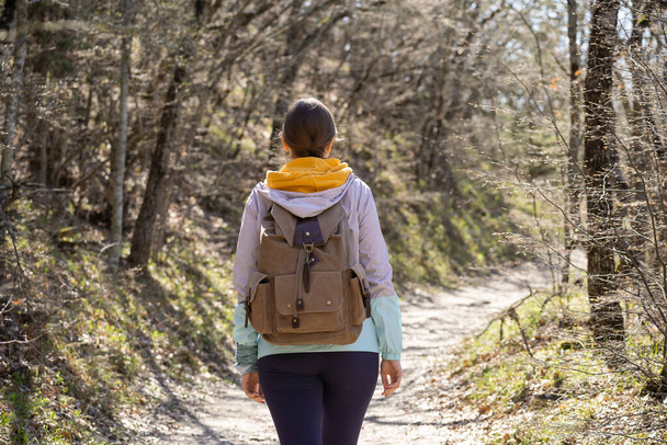 A woman with a large backpack walks along a forest path. Craving for adventure and uncharted places. - Foto, Imagem