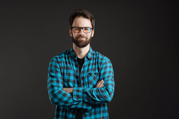 Bearded happy man in eyeglasses smiling and looking at camera isolated over black background - Фото, изображение