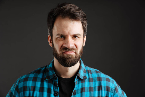 Bearded displeased white man frowning and looking at camera isolated over black background - Φωτογραφία, εικόνα