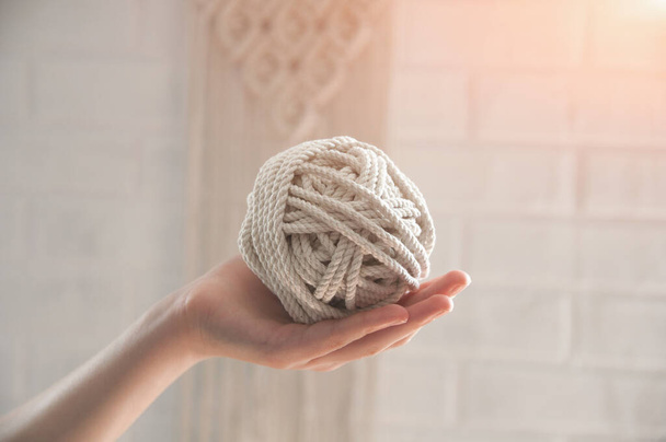 ball of yarn for knitting macrame lies on the hand against the background of a white wall - Fotoğraf, Görsel