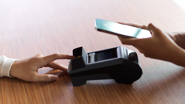 Zákazník využívající internetové bankovnictví k platbě a obdrží účtenku přes platební terminál na dřevěném stole - Fotografie, Obrázek