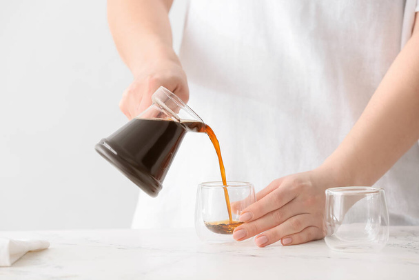 Frau gießt türkischen Kaffee aus Cezve in Tasse in Küche - Foto, Bild