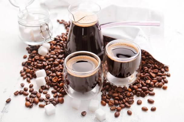 Cezve, kopjes Turkse koffie en bonen op een lichte achtergrond - Foto, afbeelding