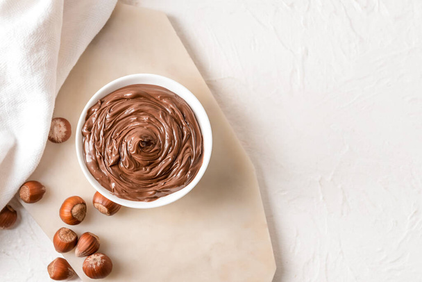 Bowl ízletes csokoládé paszta és mogyoró könnyű háttér - Fotó, kép