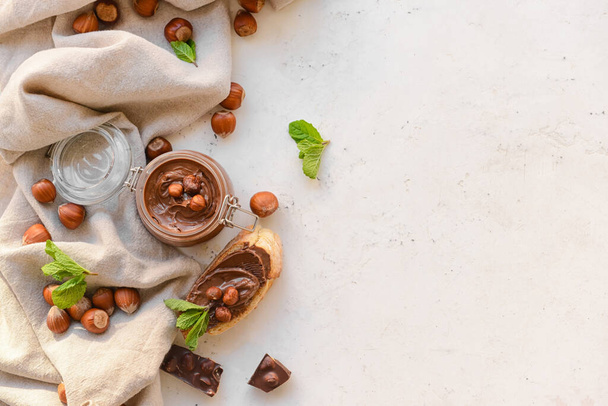 Jar ízletes csokoládé paszta és mogyoró könnyű háttér - Fotó, kép