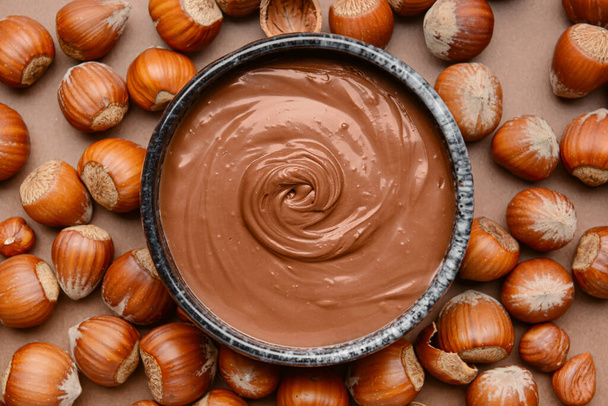 Ciotola con gustosa pasta di cioccolato e nocciole su sfondo colore - Foto, immagini