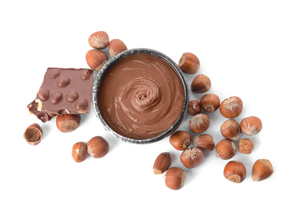 Tigela com pasta de chocolate saborosa e avelãs no fundo branco - Foto, Imagem