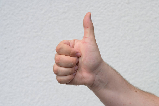 Mužská ruka dává palec nahoru gesto na bílém ukazující souhlas, souhlas, podporu, hodnocení něco jako vynikající nebo dobré nebo hlasování ano nad bílou - Fotografie, Obrázek