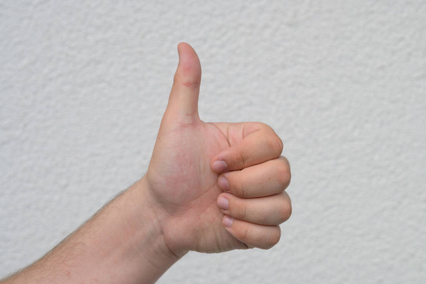 Чоловіча рука дає великий жест на білому, що показує схвалення, угоду, підтримку, рейтинг чогось відмінного або хорошого або голосування так над білим
 - Фото, зображення
