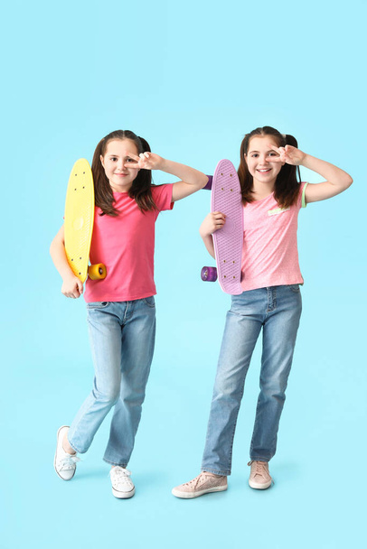Cute twin girls with skateboards on color background - Photo, Image