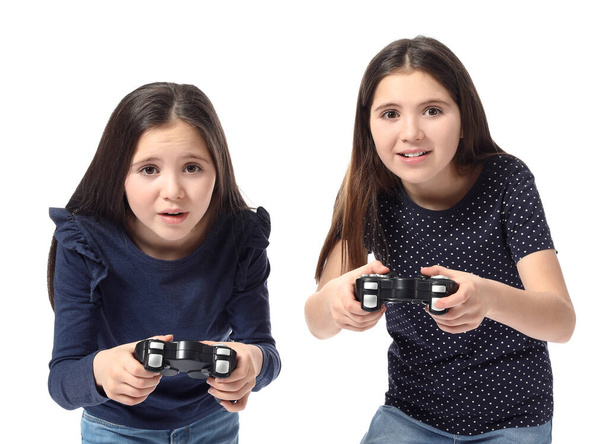 Симпатичные девушки-близнецы играют в видеоигры на белом фоне - Фото, изображение
