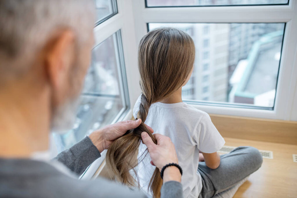 A gray-haired dad doing hair to his daughter - Valokuva, kuva