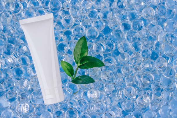 Mockup of white cream tube - natural body or face creams on blue background with water gel balls. Natural organic herbal cosmetics concept . Trendy still life composition with copy space - Foto, imagen