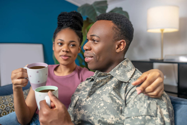 Wife hugging military husband drinking coffee - 写真・画像
