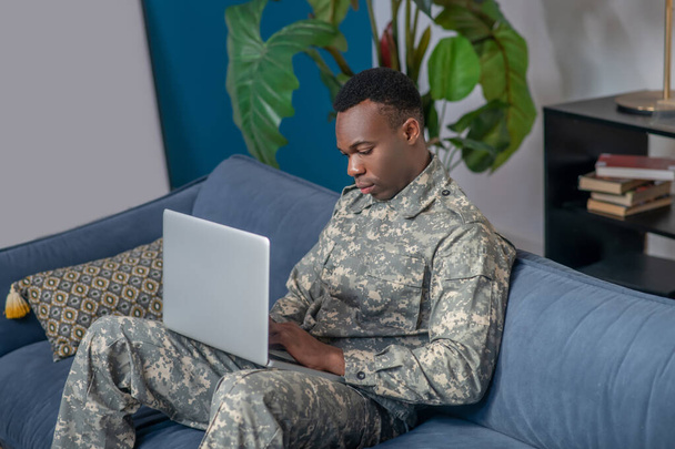 Profile of concentrated young military man with laptop - Photo, image