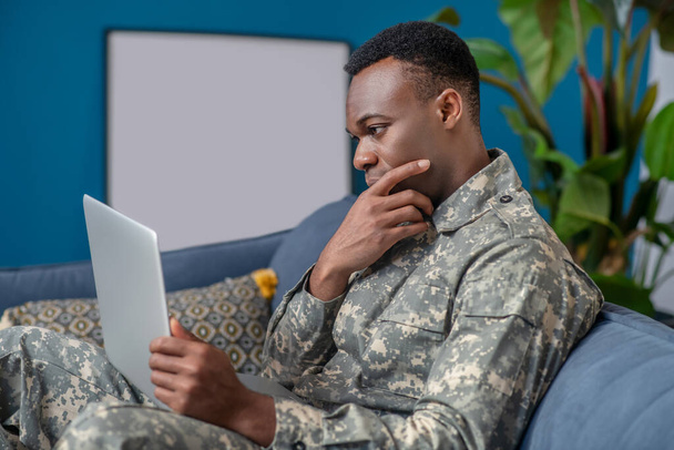 Pensive young military looking at laptop - Photo, Image