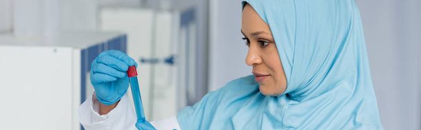 Arabian scientist in latex gloves holding test tube in laboratory, banner  - Fotó, kép