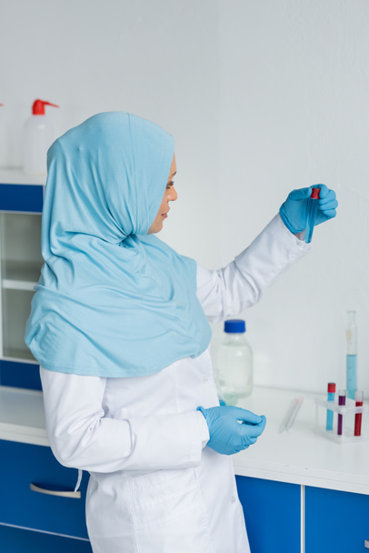 Πλευρική άποψη του αραβικού επιστήμονα σε hijab εκμετάλλευση σωλήνα δοκιμής  - Φωτογραφία, εικόνα
