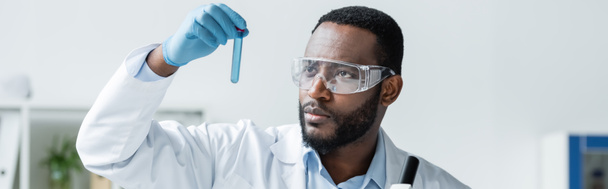 Afro-Amerikaanse wetenschapper in veiligheidsbril houden reageerbuis, banner  - Foto, afbeelding