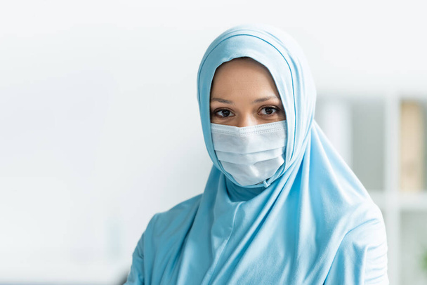 Arabian lekarz w masce medycznej i hidżab patrząc w aparat  - Zdjęcie, obraz